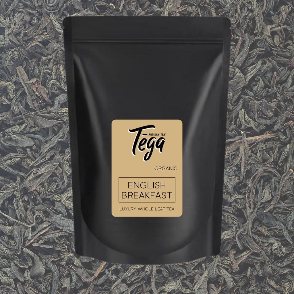 Black tea package with 'Tega' label on a background of loose tea leaves