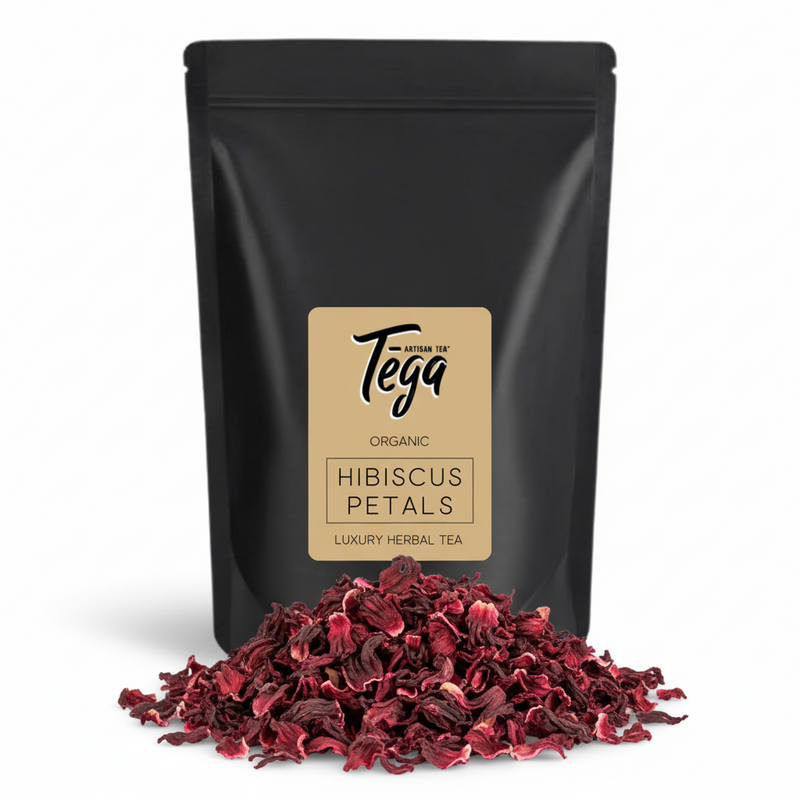Black package of Tega Organic Hibiscus Petals with dried petals in front on a white background
