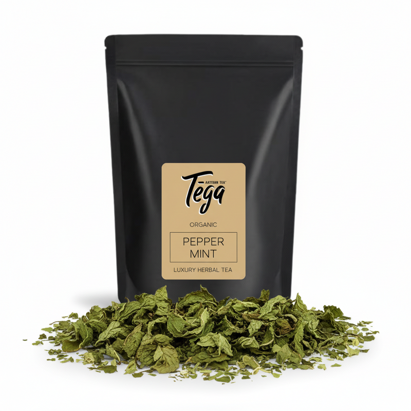 Black tea packaging with Tega label and peppermint leaves on a white background
